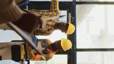 Dikey video: Depoda stok envanteri üzerinde çalışan bir grup adam, tarayıcı ile mal kodlarını tarıyor ve pano listesini kontrol ediyor. İki depo çalışanı barkodları taramak için tablet kullanıyor. Üçayak atışı
