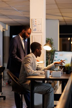 Corporate workers looking at financial statistics on computer, discussing financial strategy in startup office. Executive managers working late at night at investment plan. Business concept