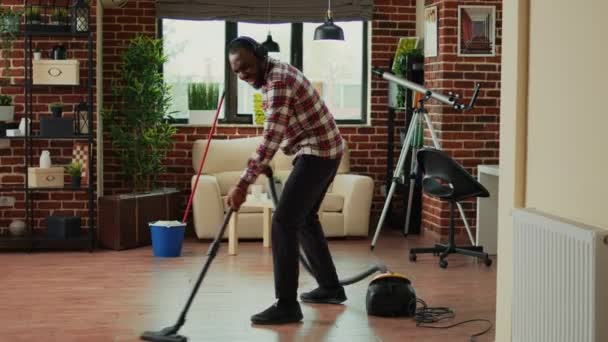 Африканский Американец Танцует Пылесосит Домашние Полы Поет Слушает Музыку Гарнитуре — стоковое видео