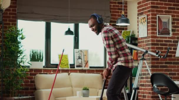 Modern Cheerful Adult Using Vacuum Cleaner Clean Apartment Floors Listening — Stockvideo
