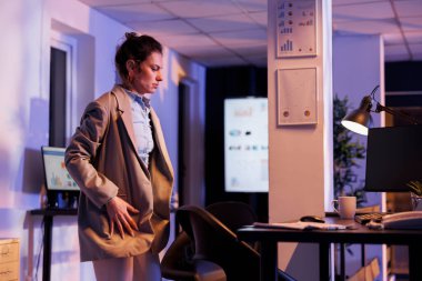 Overworked entrepreneur preparing to leave corporate job late at night, after working overhours at financial investment strategy to increase company profit. Businesswoman leaving startup office