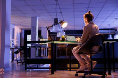 Advisor agent analyzing marketing graphs on laptop computer, working overtime at company growth report in startup office. Young entrepreneur typing financial statistics, planning strategy