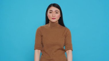 Asian maid smiling at camera while putting rubber glove after finishing house cleaning, standing in studio. Housekepper was skilled in the art of housekeeping, ensuring every surface was clean