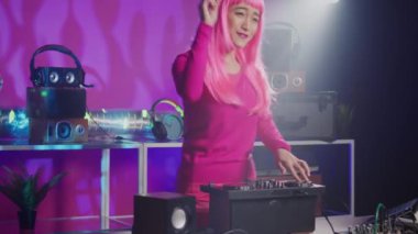 Dj artist using professional turntables in nightclub, mixing techno sound creating unique remix for fans. Asian musician with pink hair performing musical album, playing eletronic music