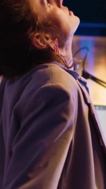 Vertical video: Company worker taking break to stretch back in office, trying to relieve pain after working overtime under pressure. Young woman stretching and analyzing diagrams on computer. Handheld