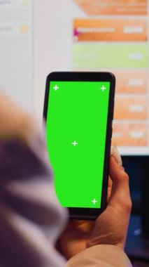Vertical video: Advisor agent using mobile phone with green screen to work on corporate development. Professional manager analyzing isolated copyspace template, blank mockup chromakey display.