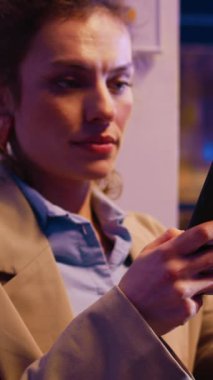 Vertical video: Startup worker browsing website on smartphone, planning new investment prooject before deadline. Employee working at desk checking online analytics to create report. Handheld shot.
