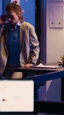 Vertical video: Young adult feeling tired working overtime on report yawning and working on increasing profit. Sleepy exhausted employee planning investment for business growth and development.