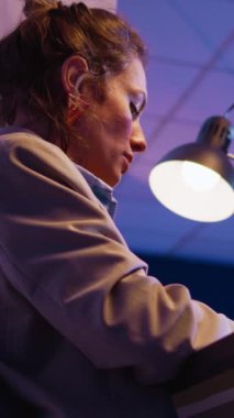 Vertical video: Executive manager typing data on computer, working late at night to plan financial investment for business growth. Young woman sitting at desk looking at analytics diagrams. Handheld