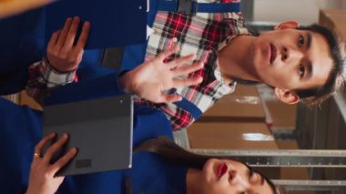 Vertical video: Asian people analyzing stock with tablet and papers, working on products distribution for business development. Team of employees organizing merchandise and supplies. Handheld shot.