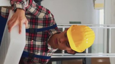 Vertical video: Wheelchair user checking inventory on laptop in storage room, working with young man to send merchandise packages. Woman with chronic disability doing quality control, business plan.