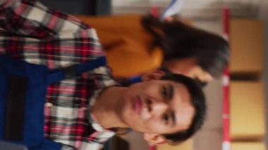 Vertical video: Young man promoting products on online ad video, recording promotion for internet channel. Male adult creating advertisement with mobile phone, filming marketing vlog. Handheld shot.