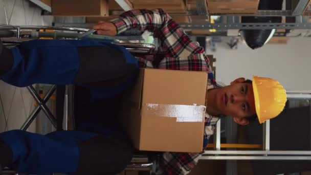 垂直视频 有缺陷的男性员工从储藏室的货架上取下盒子 整理货架上的商品 坐在轮椅上的青年男子与妇女谈论商业发展和 — 图库视频影像
