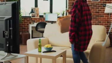 Gülümseyen kişi eve servis yemeği sipariş ediyor, TV 'de film ya da TV programı izliyor ve paket servis poşetinden fast food yiyor. Modern yetişkin TV 'de film izleyip bira içiyor..