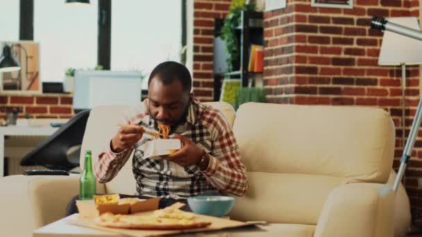 Tânăr Relaxat Folosind Beţişoare Pentru Mânca Tăiţei Distrează Uitându Film — Videoclip de stoc
