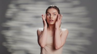 Confident woman using moisturizing facial cream for beauty routine, creating new ad campaign for glowing products. Cheerful sensual girl posing on camera to advertise nourishing luminous look.