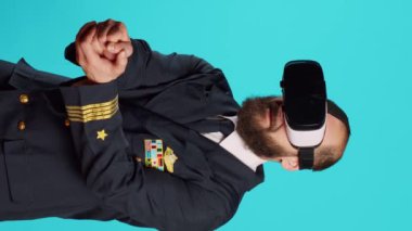 Vertical video: Airplane pilot using vr headset with interactive vision, having fun with virtual reality glasses. Young airline captain with aviaton uniform using 3d simulation gadget, aircrew.