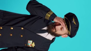 Vertical video: Sick airplane pilot suffering from headache, being worried about painful migraine and feeling ill. Professional airline captain being unhappy and in pain, feeling pressure rubbing