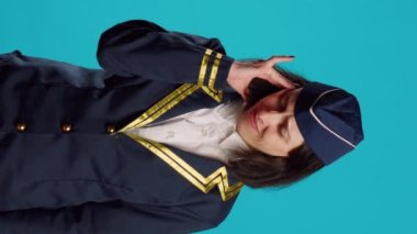 Vertical video: Female airliner dealing with painful migraine, suffering from headache on camera and feeling unhappy. Sick air hostess in uniform suffering from headache, being worried about illness.