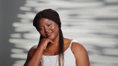 Smiling woman promoting self love in empowering ad, filming skincare campaign in studio. Natural girl with radiant appearance feeling flawless and confident on camera, bodycare.