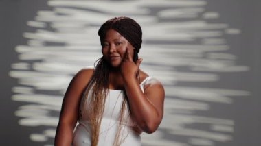 Young person embracing imperfections on camera, posing for empowering skincare ad campaign. Positive gentle woman with natural radiant skin feeling confident with body and skintone.