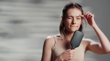 Happy person singing music with hair brush in studio, fooling around being silly and showing confidence. Smiling woman with luminous skin having fun with beauty skincare ad campaign.