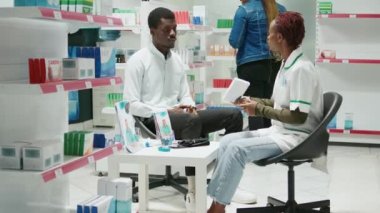 Young adult asking specialist about pills medication, looking at boxes of medicaments and supplements. Customer and pharmacist talking about drugs cure from pharmacy health center.
