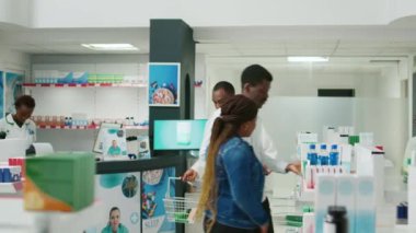 Male specialist putting stock of medicaments and drugs on pharmacy shelves, putting boxes of pills and vitamins to help clients. Young adult working with pharmaceutical products, healthcare.