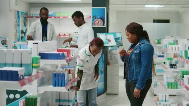 Female Pharmacist Helping Customer Medicine Showing Pharmaceutical Products Drugstore Shelves — Stockvideo