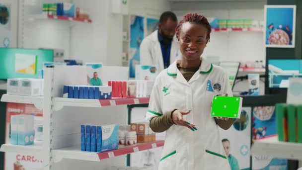 健康专家在药店用绿屏指著医药盒 播下孤立的色键模板 药店背景空白的年轻员工 — 图库视频影像