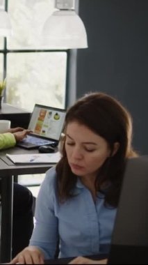 Dikey video: Şirket çalışanı iş ofisindeki kar artışı için yatırım stratejisi planlamak için online analitik kullanıyor. Dizüstü bilgisayarı ve veri istatistikleri ile başlangıç geliştirme üzerinde çalışan genç bir kadın.