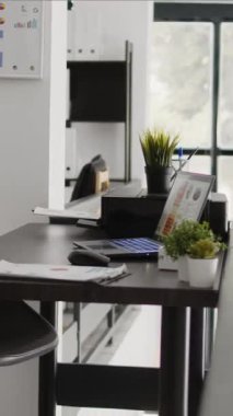 Dikey video: Çalışma masası ve çalışma masası olan boş şirket ofisi, belge ve bilgisayarlarla dolu iş geliştirme alanı. Şirket odası kariyer geliştirme ve başarı için kullanılıyor.