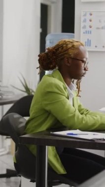 Vertical video: African american office worker planning research project, using online analytics on computer. Female manager using statistics to plan new investment report, business career development