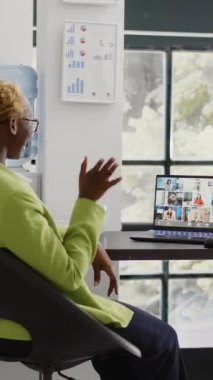 Vertical video: Team leader using internet remote conference on pc, talking to corporate employees about growth. Female entrepreneur chatting on teleconference call, videocall meeting in coworking
