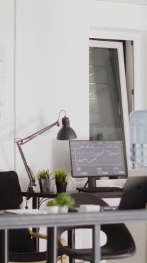 Dikey video: Birden fazla masası olan profesyonel şirket çalışma istasyonları, yönetim kurulu iş aletleri ve bilgisayarlarla dolu boş bir alan. Kurumsal içişlerinde dijital ajans çalışma alanı.