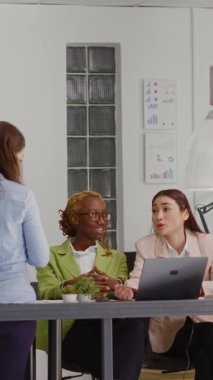 Vertical video: Employees team planning development in meeting, talking about startup collaboration and looking at papers with analytics. Colleagues thinking about business solutions in agency office.