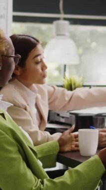 Vertical video: Business team meeting to discuss development strategy in boardroom office, brainstorming ideas about marketing vision and profit growth. Diverse people talking about executive project.