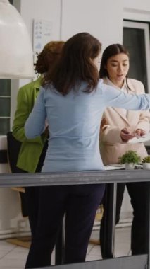 Vertical video: Multiethnic team of people planning annual report together, working on corporate partnership in startup office. Group of women discussing new business strategy and solutions in
