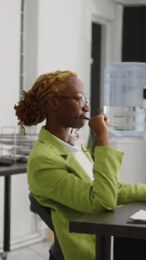 Vertical video: African american woman thinking about marketing vision and working on business development plan. Corporate employee brainstorming new ideas and solutions, help increase profit.