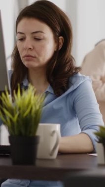 Vertical video: Agency employee working in corporate office with pc, analyzing online data statistics on computer screen. Young entrepreneur looking at company results and analytics. Handheld shot.