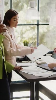 Vertical video: Diverse team of workers planning analytics report, working on business partnership in coworking space. Group of employees discussing new marketing strategy and vision in agency office.