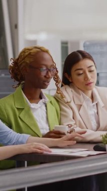 Vertical video: Multiethnic people presenting analytics report in office, planning business development to increase profit. Young colleagues attending corporate meeting for online investment plan.