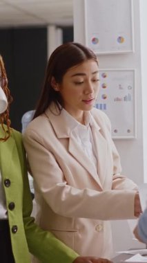 Vertical video: Team of office workers discussing about marketing vision brainstorming results before planning corporate investment. Business women analyzing annual data report, collaboration.