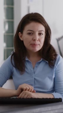 Vertical video: POV of entrepreneur meeting on telework videocall with colleagues, using online teleconference call to talk to people at office desk. Female employee chatting on internet conference