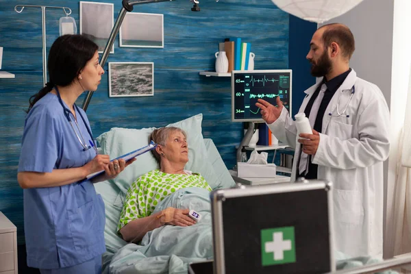 Medical Team Attending Elderly Woman Lying Bed Hospital Room Explaining — Stockfoto
