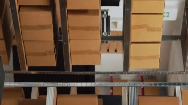 Dikey video: Müşterilere yollamak için kutularda ürünler, tedarik zinciri dağıtımında kullanılan karton paketlerdeki ürünlerle dolu bir başlangıç alanı. Malla birlikte boş depo ve