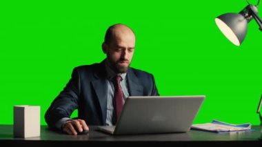Businessman over greenscreen feeling tired and stressed, sitting laid back at desk. Team leader working over chroma key backdrop with isolated mockup template, exhausted adult.