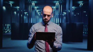 Donanım dijitalleştirmesi, bulut hesaplama ve küme bilgisayarı için tablet kullanan erkek altyapı uzmanı. Veri merkezi teknisyeni sunucu taraması yapıyor. Üçayak atışı.