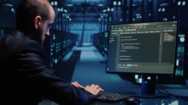 Erkek sistem mühendisi bilgisayardaki büyük verileri analiz ediyor, bulut hesaplama ağını ve dijital sunucuları kontrol ediyor. Dijitalleştirme için modern veri merkezini inceleyen genç bir bilişim teknisyeni. El kamerasıyla..