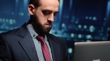 Male professional server IT engineer using laptop in data center, working on computer mainframe processor and running diagnostics on cloud computing connection, artificial intelligence. Handheld shot.
